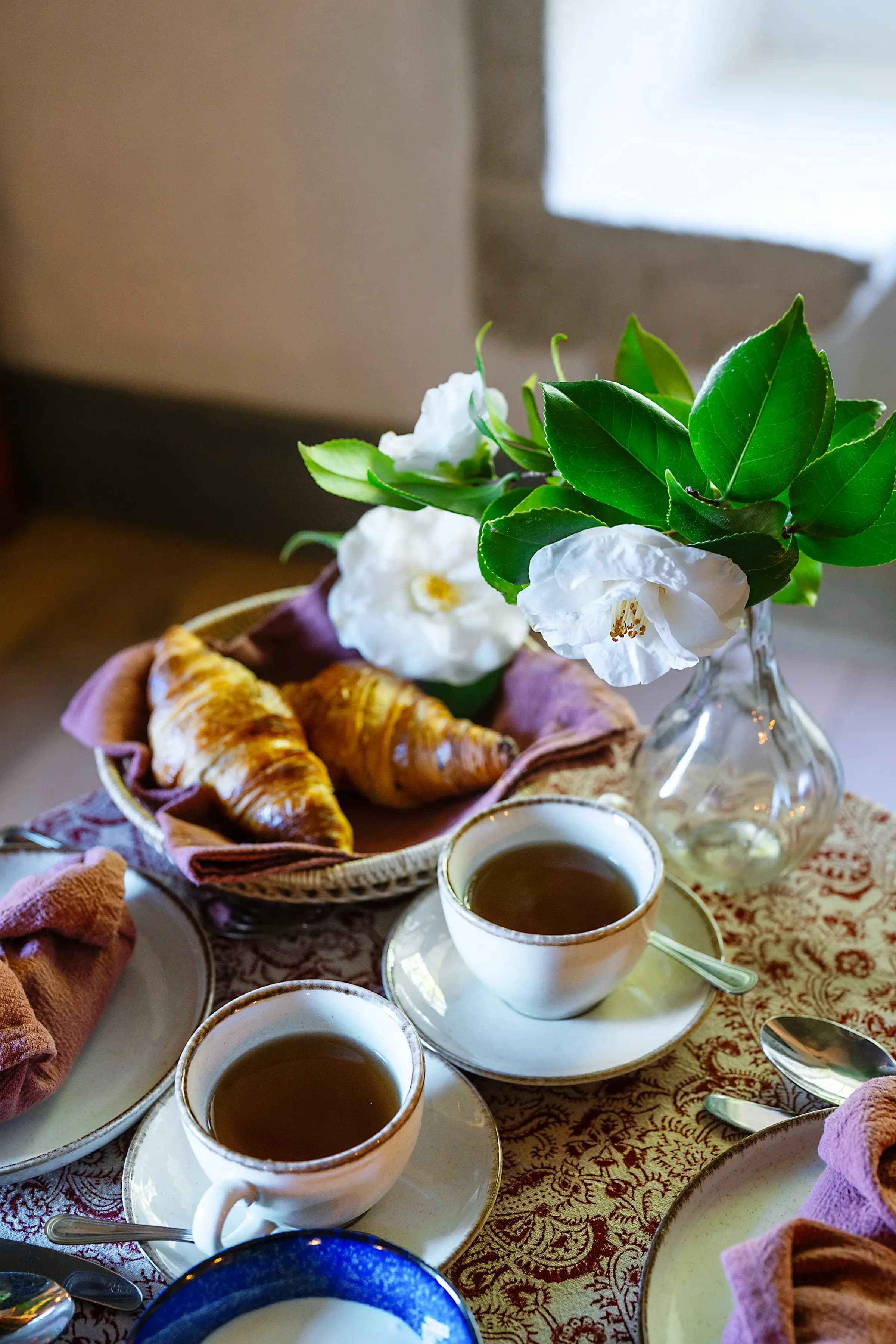 Tabuleiro de pequeno-almoço com croissants, café e gardénias