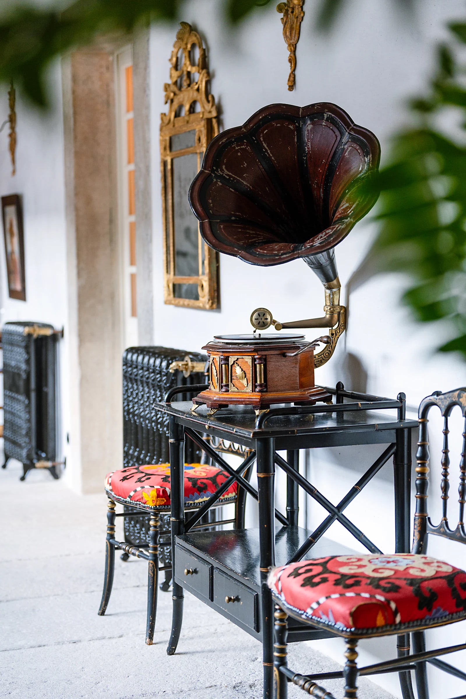 An antique gramophone on a lacquered side table in the cloister gallery, gilded mirror behind